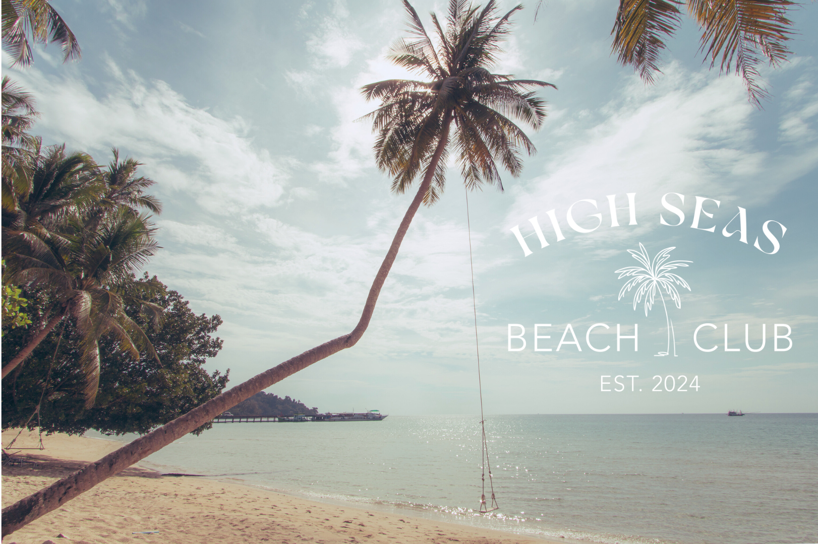 Curved palm tree with swing on tropical beach, High Seas Beach Club logo overlay, calm ocean view